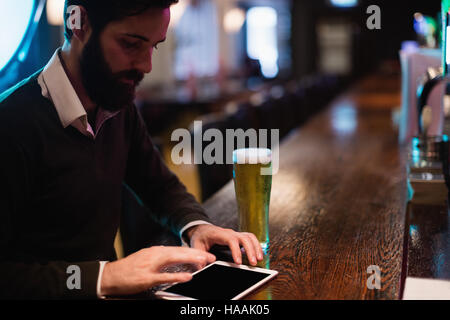 Businessman using digital tablet with glass of beer on counter Stock Photo