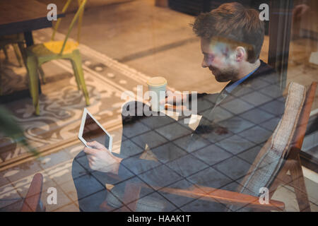 Businessman holding disposable coffee cup and using digital tablet Stock Photo