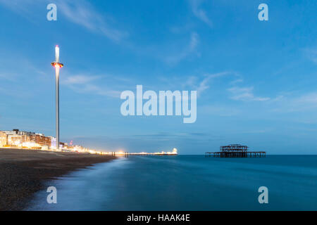 Night Photo of Brighton Skyline with old West Pier, Central Pier with fun fair lights and the new i360 attraction Stock Photo