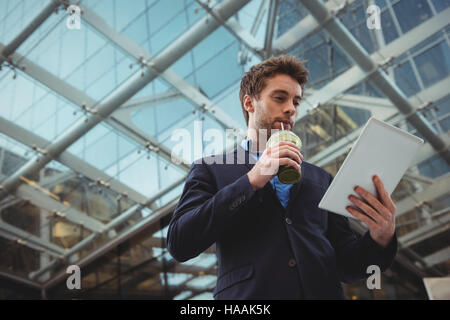 Businessman using digital tablet while having juice Stock Photo
