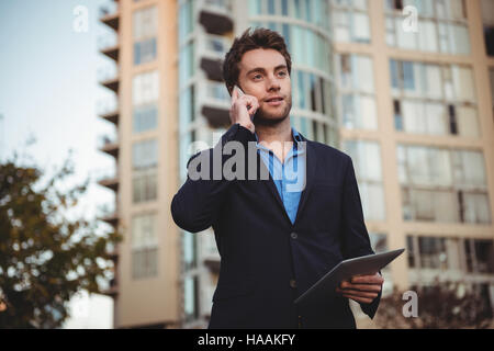 Businessman talking on mobile phone and holding digital tablet Stock Photo
