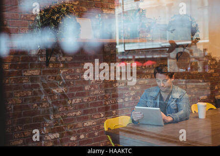 Man using digital tablet with coffee cup on table Stock Photo