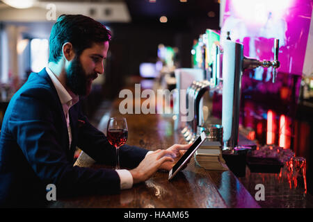 Businessman using digital tablet with wine glass on counter Stock Photo