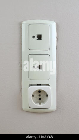 Three old used sockets on a wall- two for network cable and one for electric plug Stock Photo