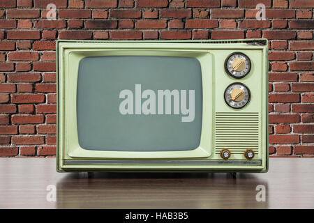 Grungy green vintage television set with brick wall. Stock Photo