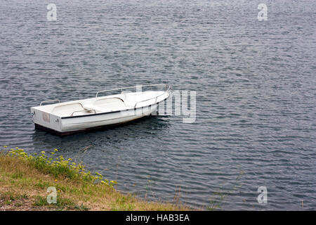White rowboat anchored near meadow in adriatic Stock Photo
