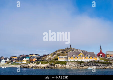 View across Colonial Harbour (Kolonihavnen) to old hospital and Hans Egede statue on a hilltop beside cathedral in summer 2016. Nuuk Greenland Stock Photo