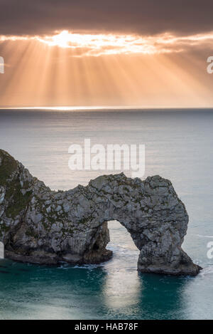 Lulworth, Dorset, UK.  28th November 2016.  UK Weather.  Beams of sunlight shine through a break in the thinning cloud above Durdle Door in Dorset after an overcast start to the day. Picture: Graham Hunt/Alamy Live News
