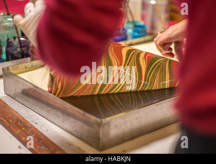 Traditional Turkish art Ebru in process. Woman picking up the finished artwork from the ebru tray with water. Stock Photo