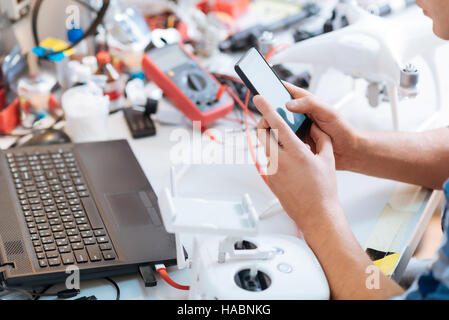 Close up of mans hands using smartphone and laptop Stock Photo