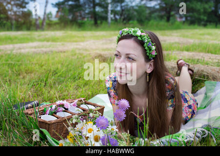 Freckled girl lying on plaid in meadow and looking away Stock Photo