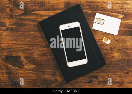 Switching SIM cards in smartphone, top view of mobile phone device on desktop Stock Photo