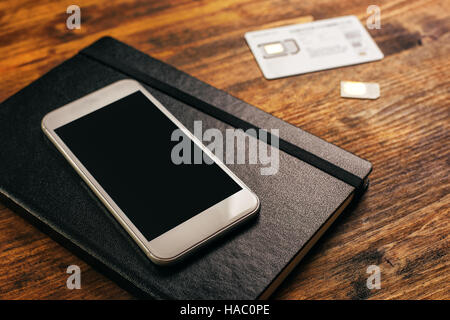 Switching SIM cards in smartphone, top view of mobile phone device on desktop Stock Photo