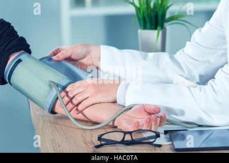 Doctor cardiologist measuring blood pressure of female patient in hospital office, health care control and monitoring Stock Photo