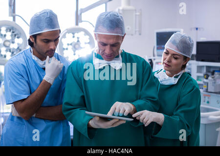 Team of surgeons discussing over digital tablet in operation room Stock Photo