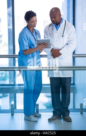 Male doctor and nurse using digital tablet in corridor Stock Photo