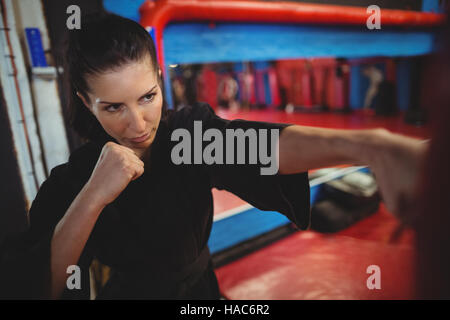 Female karate player practicing boxing with punching bag Stock Photo