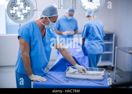 Surgeon removing surgical tools from tray in operation room Stock Photo