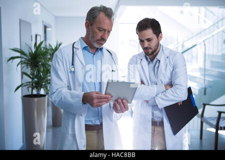 Doctors having discussion over digital tablet in corridor Stock Photo