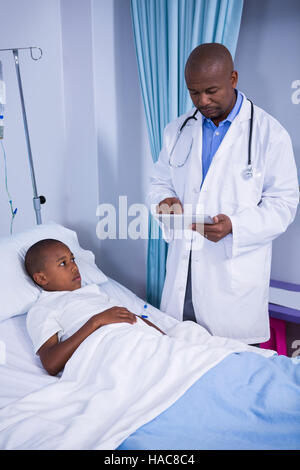 Male doctor using digital tablet during visit in ward Stock Photo