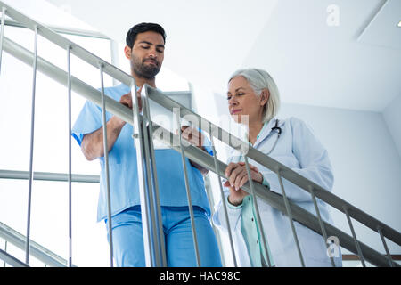 Doctors discussing over digital tablet while standing on stairs Stock Photo