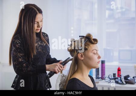 Long hair being straightened with iron by stylist Stock Photo