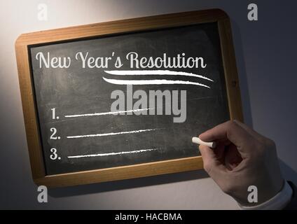 Hand writing new year resolution goals on slate board Stock Photo