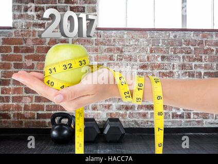 Hand holding green apple wrapped with measuring tape against 3D 2017 Stock Photo