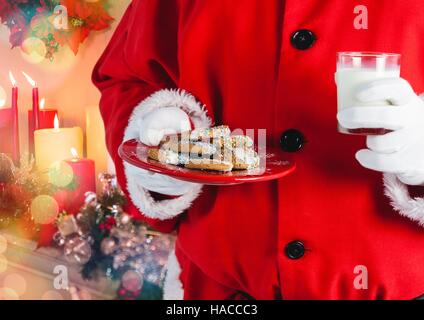 Santa hand holding cookies and a glass of milk Stock Photo
