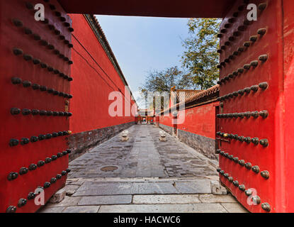Red ancient wooden massive door gates with bronze knobs in Chinese emperors forbidden city to separate residential sections from visitors. Stock Photo