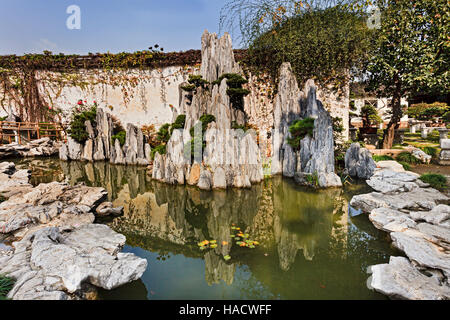 Mini rock formation from still water pond in a public garden of Suzhou city in China on a bright sunny autumn day. Stock Photo