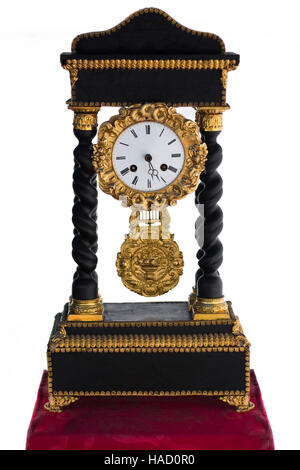Antique black and gold Clock on red velvet table isolated Stock Photo