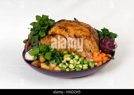 A roasted Christmas turkey complete with Brussels Sprouts, roast potatoes, carrots and stuffing in a large round dish.a UK Stock Photo