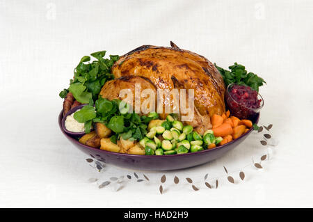 A roasted Christmas turkey complete with Brussels Sprouts, roast potatoes, carrots and stuffing in a large round dish.a UK Stock Photo