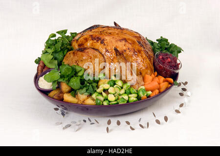 A roasted Christmas turkey complete with Brussels Sprouts, roast potatoes, carrots and stuffing in a large round dish.a UK Stock Photo