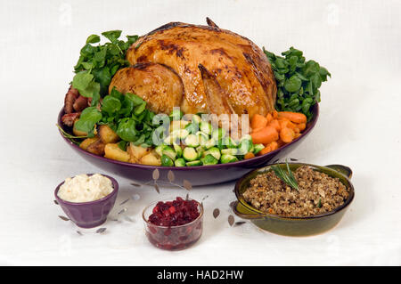 A roasted Christmas turkey complete with Brussels Sprouts, roast potatoes, carrots and stuffing in a large round dish.a UK Stock Photo