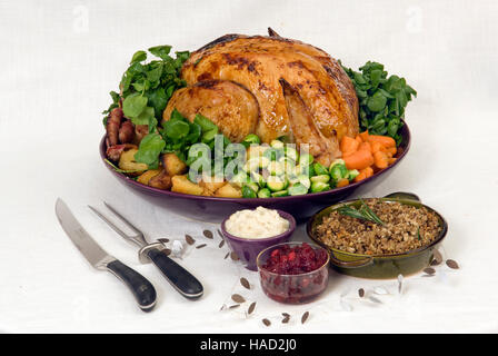 A roasted Christmas turkey complete with Brussels Sprouts, roast potatoes, carrots and stuffing in a large round dish.a UK Stock Photo