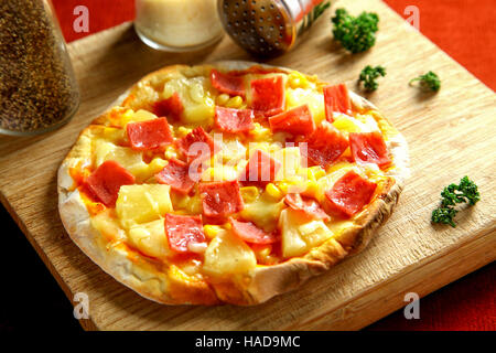 Ham and pineapple pizza on wooden table Stock Photo