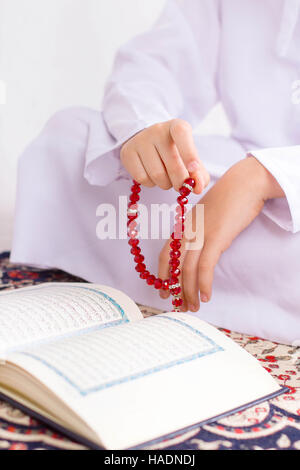 Muslim Kid in Ramadan , Reading Quraan , making zikr using rosary Stock Photo