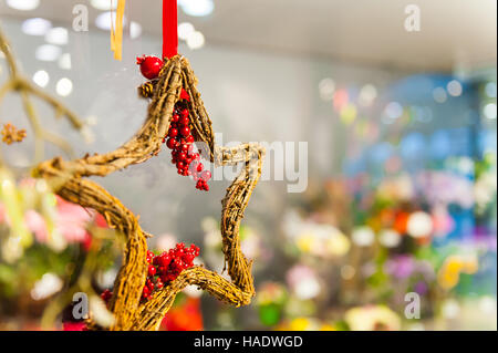 Wooden star of branches with clusters red berries hanging on the tape or ribbon other decorations and garlands. copy space. Stock Photo