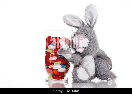 Easter bunny soft toy with candy easter eggs in a glass Stock Photo