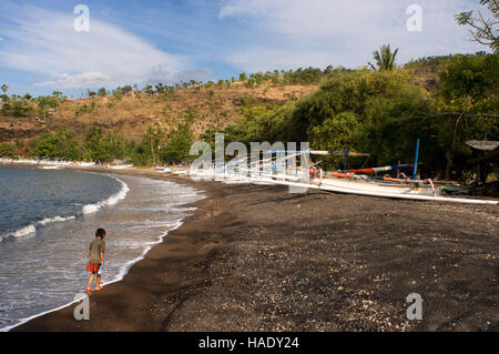 The boats rest on the sandy beach of Amed, a fisherman village in East Bali. Amed is a long coastal strip of fishing villages in East Bali. Amed refer Stock Photo