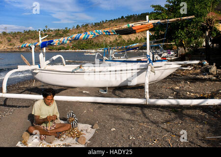 A fisherman with several fishing boats on the beach of Amed, a small fishing village in East Bali. Amed is a long coastal strip of fishing villages in Stock Photo