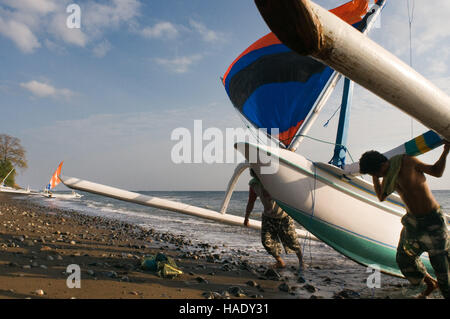 Some fishermen take their boats to the shore near the beach of Amed, a fisherman village in East Bali. Amed is a long coastal strip of fishing village Stock Photo