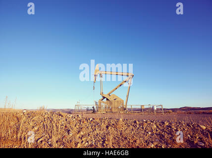 Retro toned picture of an oil pump at sunset. Stock Photo