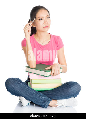 Full body young Asian female student in pink shirt with textbooks, seated on floor, full length isolated on white background. Stock Photo