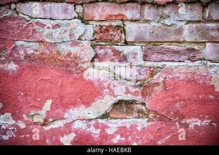 Decaying wall grunge texture. Red paint and exposed brick with plaster falling off Stock Photo