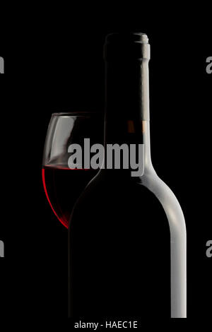 Elegant red wine bottle and wine glass in a black background Stock Photo