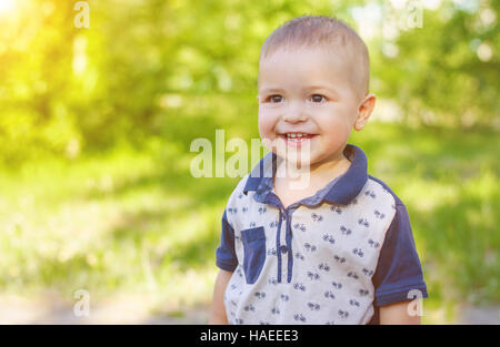 Portrait of a laughing little boy outdoors. Walk in nature with sunlight. Stock Photo