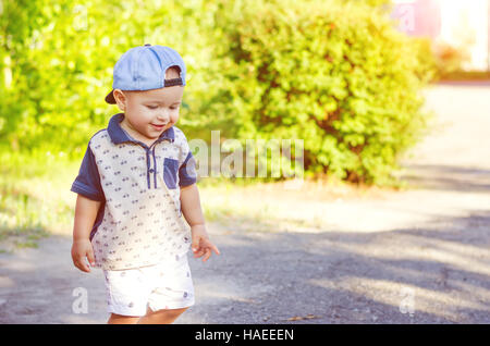 little boy wearing a cap during outdoor movement. Walk in nature with sunlight. Stock Photo